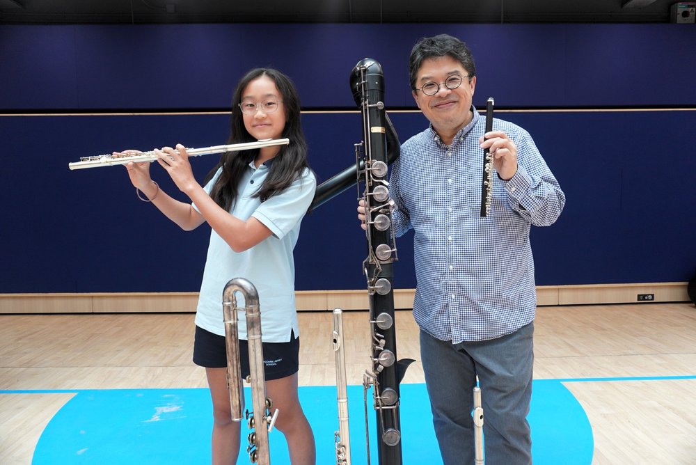 Lily and Ringo are holding a flute and a giant contrabass flute respectively for the instrumental workshop.