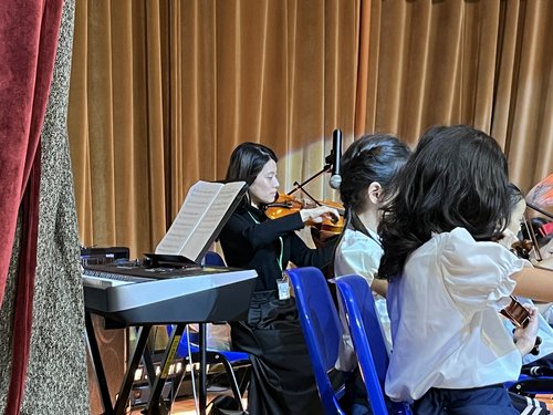 A clearer view of the teacher playing violin during the student concert, great job!