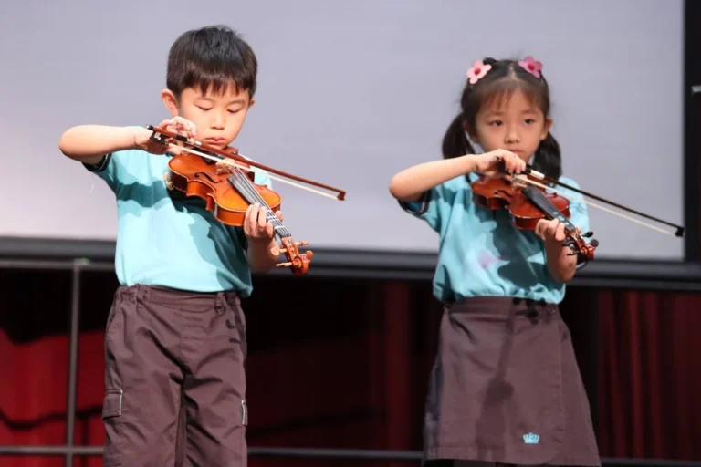 2 children at NAISHK is having their music lessons with their violins.