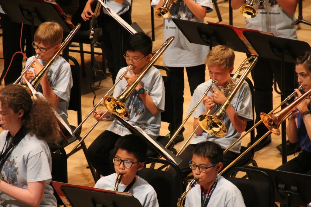 A group of students is performing on stage with their own trumpets and trombones.