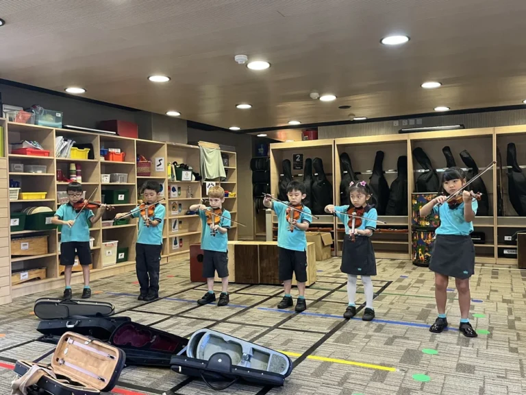 A group of students is having their NAISHK music lesson, performing in front of everyone.