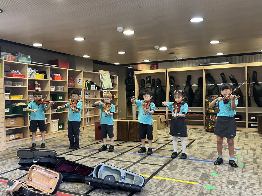 A group of students is having their NAISHK music lesson, performing in front of everyone.
